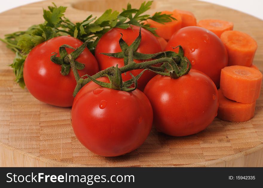 Fresh tomatoes, carrots and parsley on a wooden cutting board. Fresh tomatoes, carrots and parsley on a wooden cutting board