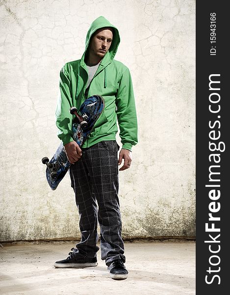 Youth stands with skateboard and green hoodie. Youth stands with skateboard and green hoodie