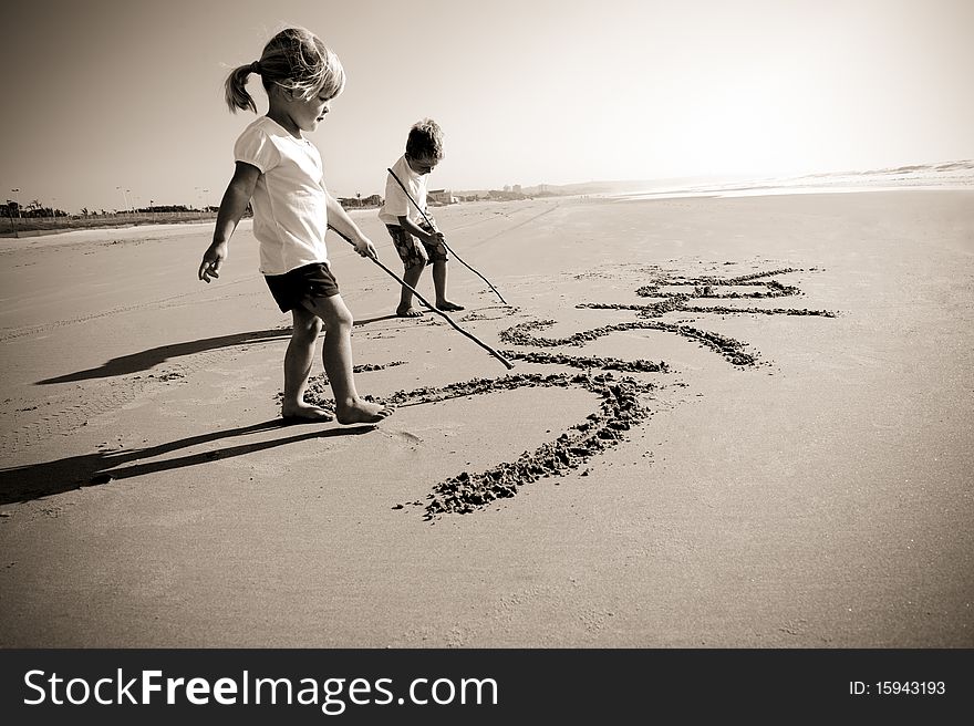 Lovely young brother and sister write words in the sand together. Lovely young brother and sister write words in the sand together