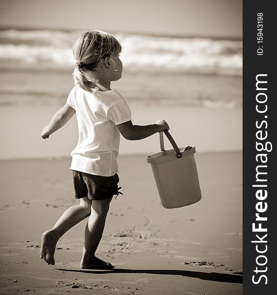 Adorable little blonde girl with her bucket at the beach. Adorable little blonde girl with her bucket at the beach