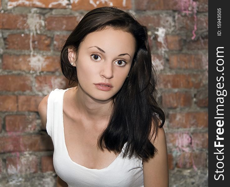 Fashion portrait of young woman with a brick wall in the background