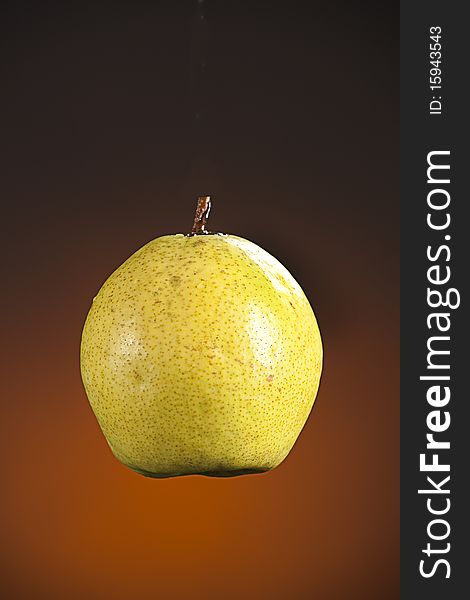 A sweet ripe pear fruit isolated against a spotlight gold background. A sweet ripe pear fruit isolated against a spotlight gold background.