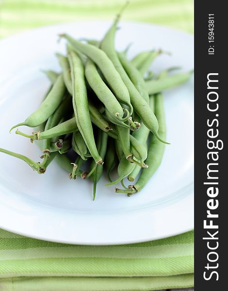 Green peas on a white plate with a green cloth