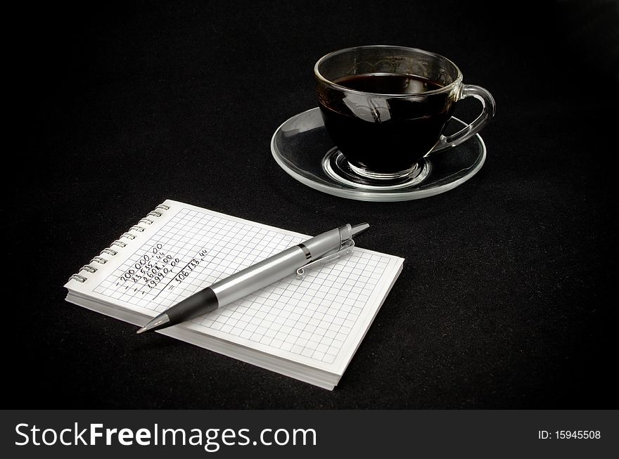 Cup Of Coffee And A Notepad With A Pen On A Dark B