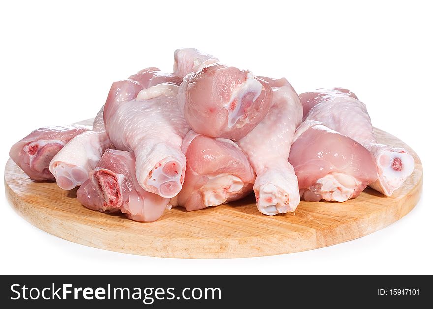 Raw chicken legs on chopping board on white background