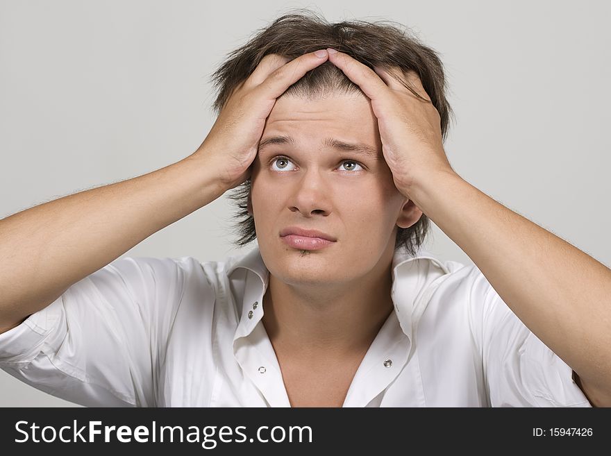 Closeup portrait of a upset young man with hand on his head