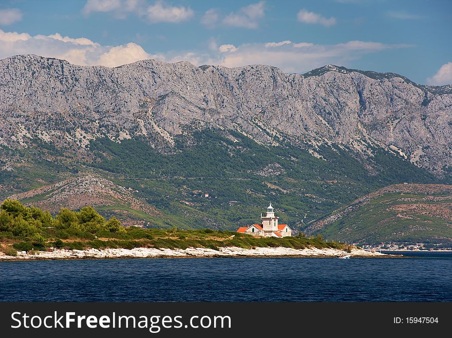 Lighthouse on Hvar island in Croatia with tall mountains in the background. Lighthouse on Hvar island in Croatia with tall mountains in the background