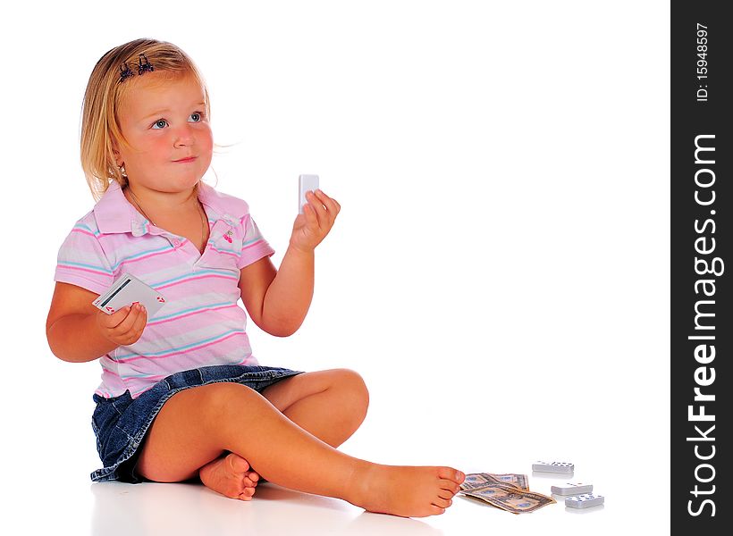 A 2-year-old girl paying with game pieces: dominoes, cards, money. Isolated on white. A 2-year-old girl paying with game pieces: dominoes, cards, money. Isolated on white.