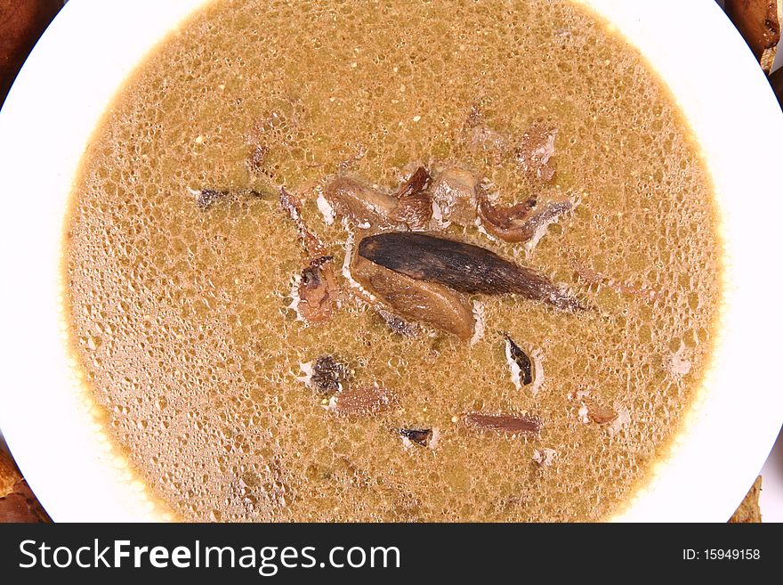 Mushroom soup on a plate surrounded by some mushrooms in close up