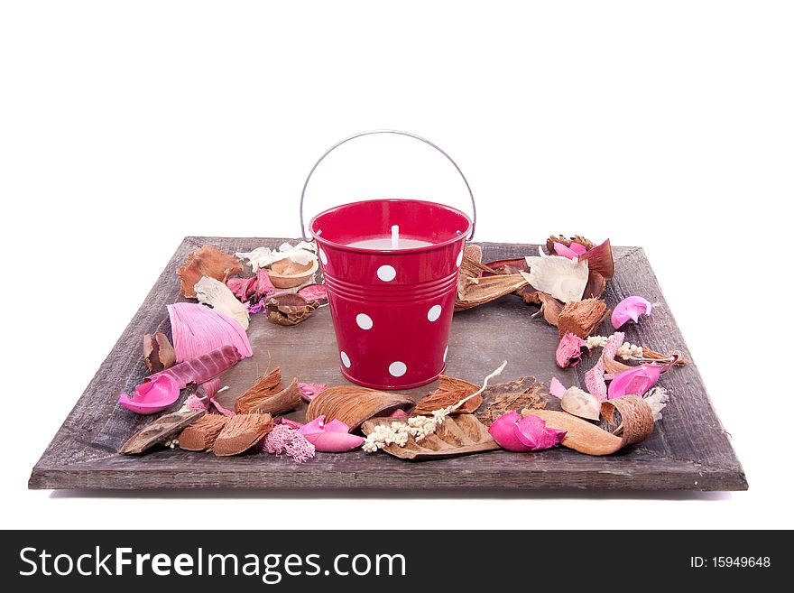 A candle in a bucket on a wooden plate with potpourri isolated over white. A candle in a bucket on a wooden plate with potpourri isolated over white
