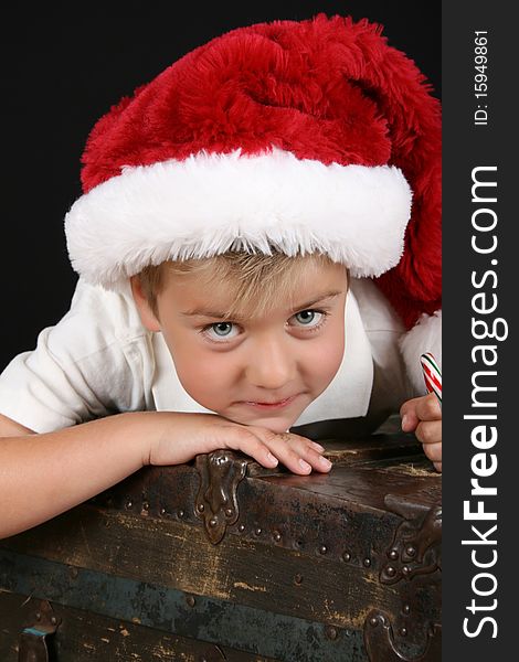 Cute young boy lying on an antique trunk wearing a christmas hat. Cute young boy lying on an antique trunk wearing a christmas hat