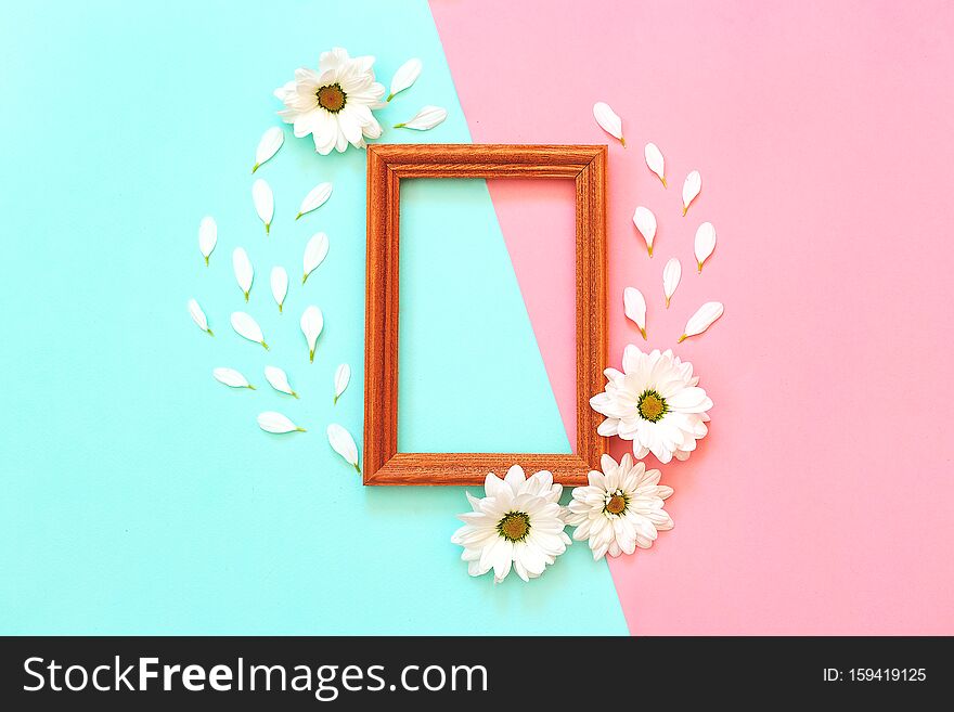 White chrysanthemum with wooden photo frame on a mint and pink background. Flat lay, top view, copy space. White chrysanthemum with wooden photo frame on a mint and pink background. Flat lay, top view, copy space