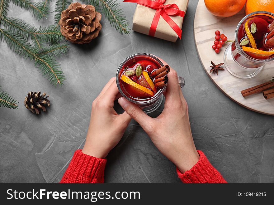 Young Woman Holding Glass Of Tasty Mulled Wine At Grey Table