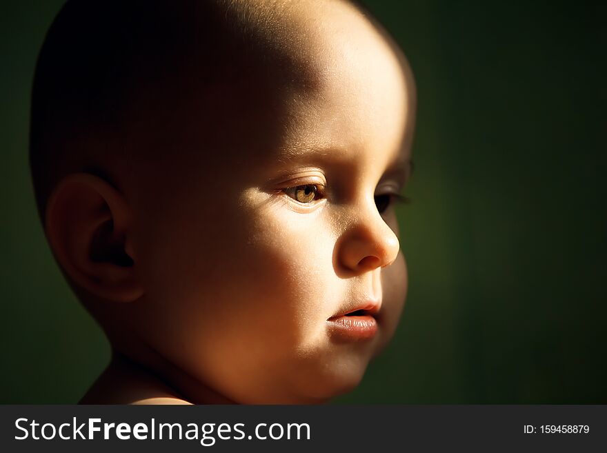 Face of a young child on a green background, rays of the sun