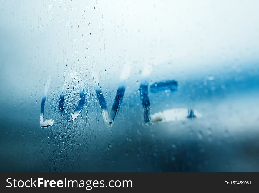 Women Hand`s drawing LOVE word on glass window with water drop concept design for valentine`s day or wedding background