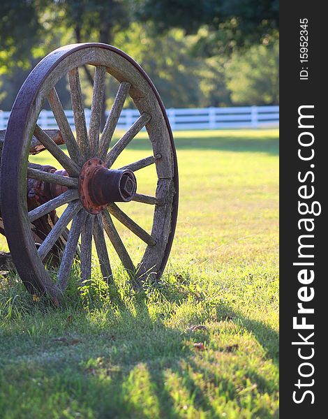 Rustic wagon wheel casting shadow on grass. Rustic wagon wheel casting shadow on grass