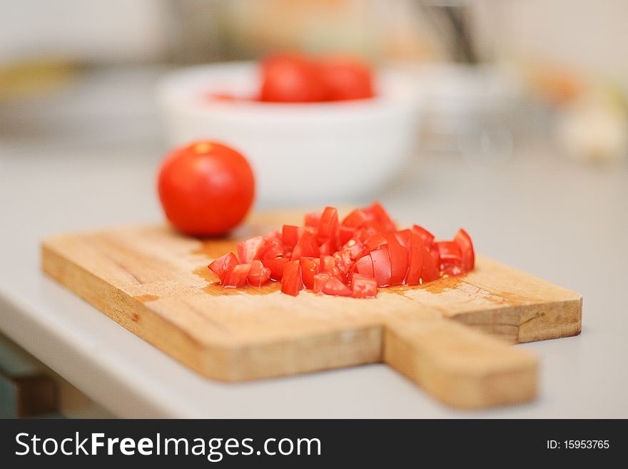 Sliced tomatoes on a wooden cutting board with a whole tomato in the background