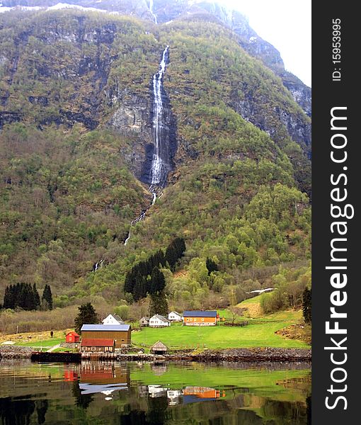 Several houses on the shore of the fjord, in the background mountains and waterfall. Several houses on the shore of the fjord, in the background mountains and waterfall