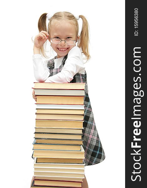Cute funny little schoolgirl standing behind the books with glasses on laughing studio shot on white background. Cute funny little schoolgirl standing behind the books with glasses on laughing studio shot on white background