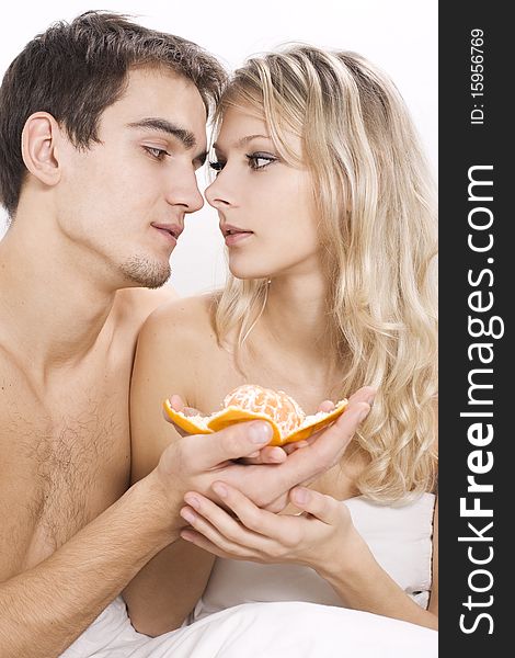Young couple enjoying fruit breakfast in bed. Young couple enjoying fruit breakfast in bed
