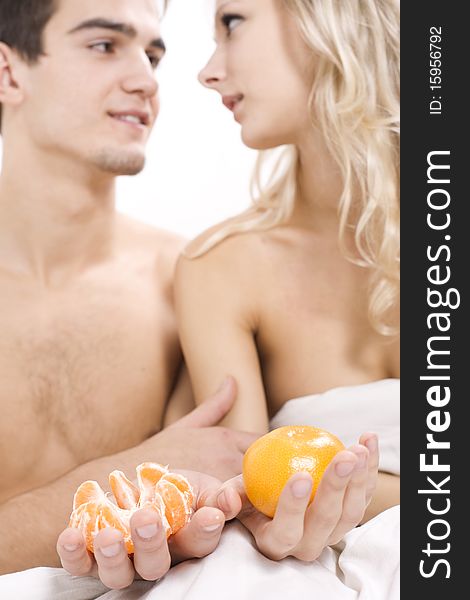 Young couple enjoying fruit breakfast in bed. Young couple enjoying fruit breakfast in bed
