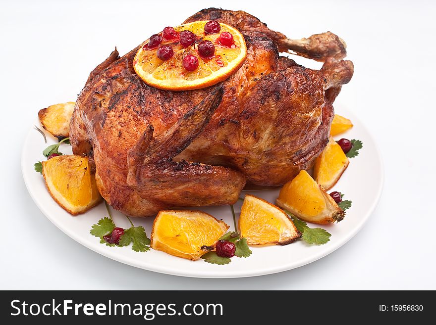 Roasted festive chicken garnished with fruit on a white background. Roasted festive chicken garnished with fruit on a white background