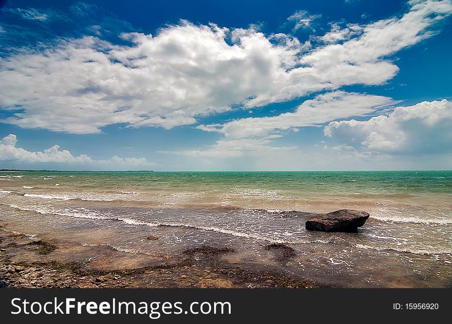 The rock laying on the seashore in the water under cloudy sky. The rock laying on the seashore in the water under cloudy sky