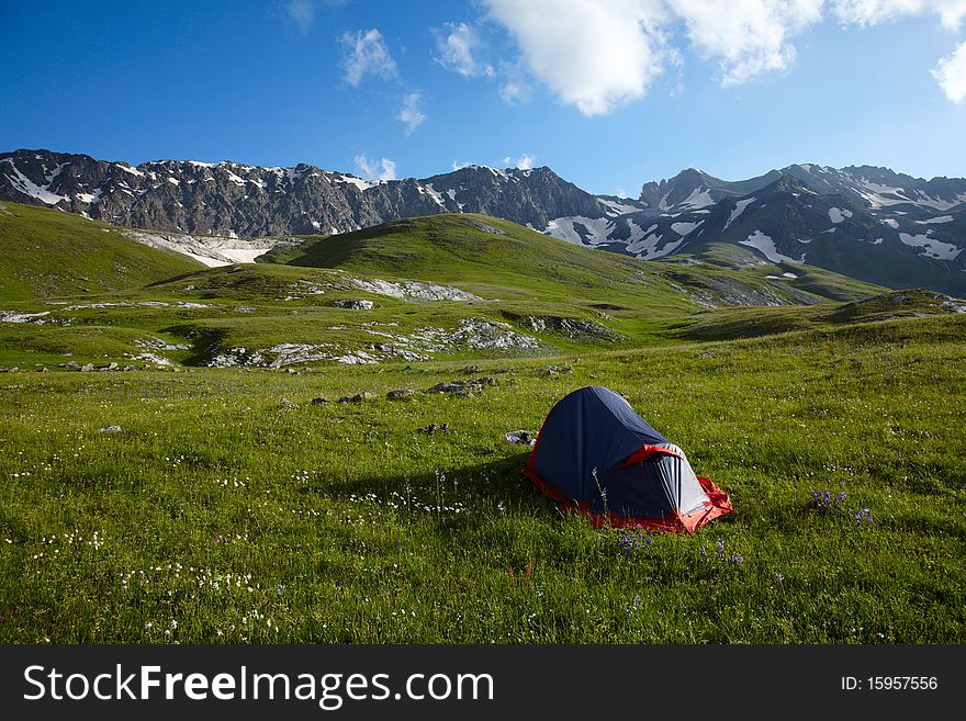 Tent on green grass in the high mountains