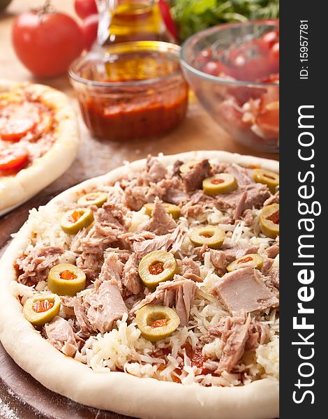 Raw tuna and green olives pizza with ingredients at the back