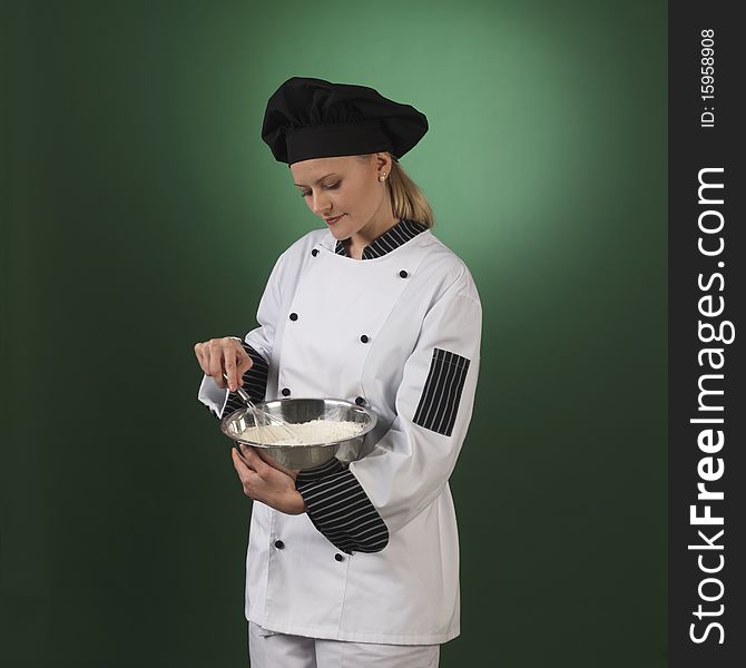 One atractive cook, she is wearing professional uniform and standing stearing a flour bowl. One atractive cook, she is wearing professional uniform and standing stearing a flour bowl.