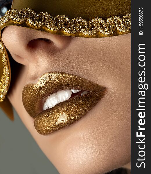 Close up view of beautiful woman lips with golden metallic lipstick. Fashion make up. Cosmetology, drugstore or fashion makeup concept. Studio shot