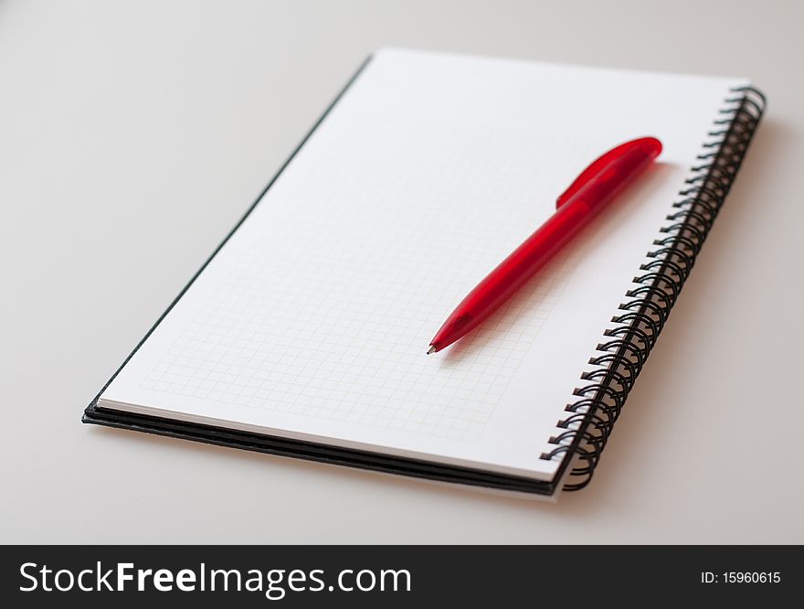 Notepad with pen on light-grey background