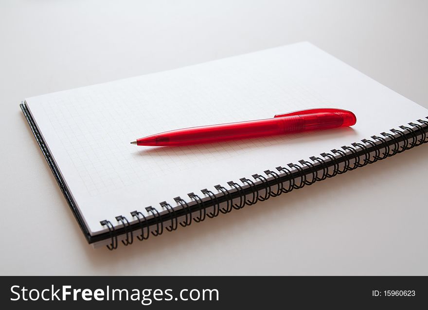 Notepad with pen on light-grey background