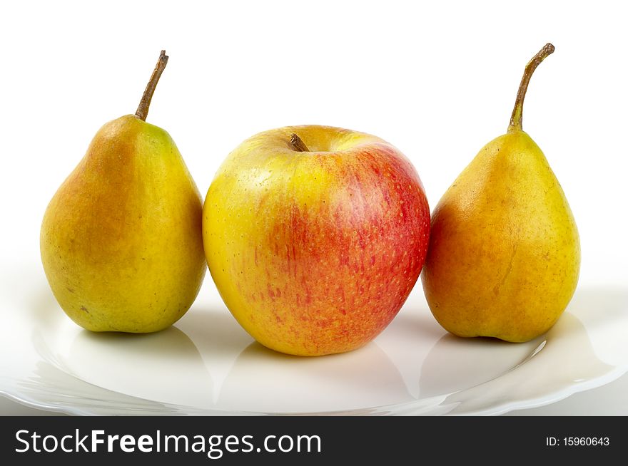 Yellow-red apple and two pears over white plate. Yellow-red apple and two pears over white plate