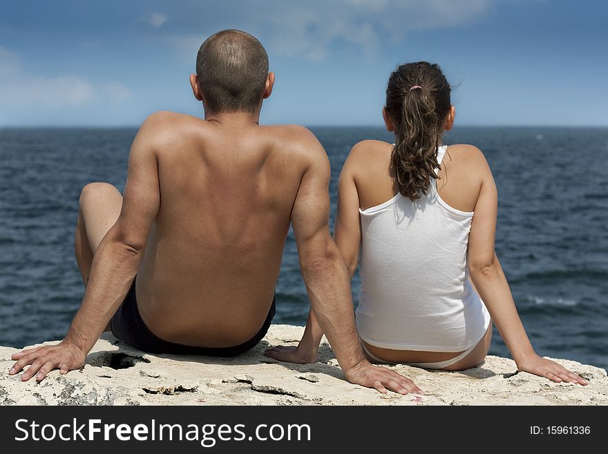 Young couple sitting on a clif
f and looking at sea. Young couple sitting on a clif
f and looking at sea