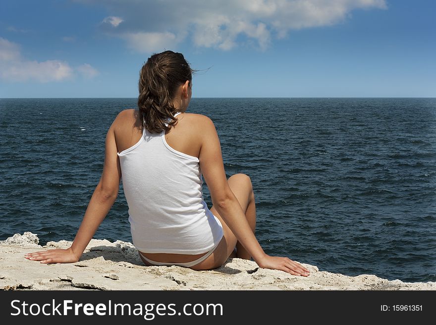 Young woman on a cliff looking at sea. Young woman on a cliff looking at sea