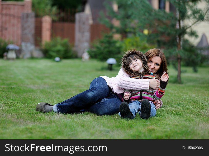 Young mother with her daughter in colorful sweaters in the garden. Young mother with her daughter in colorful sweaters in the garden