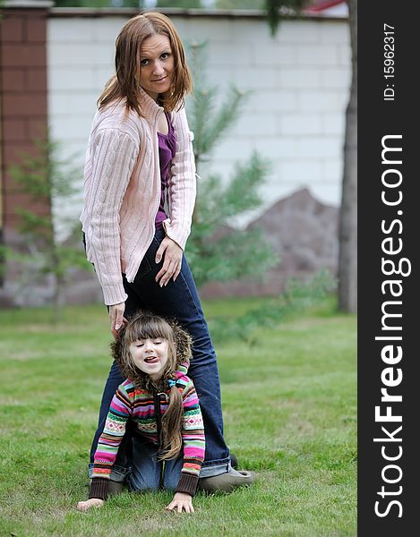 Young mother with her daughter in colorful sweaters in the garden. Young mother with her daughter in colorful sweaters in the garden