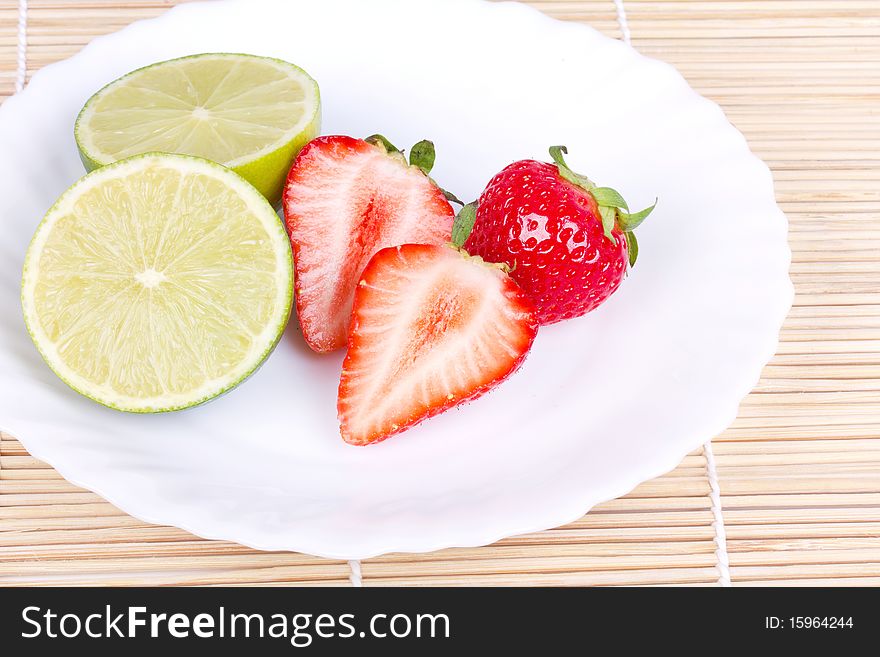 Strawberries and lime on white plate, closed-up
