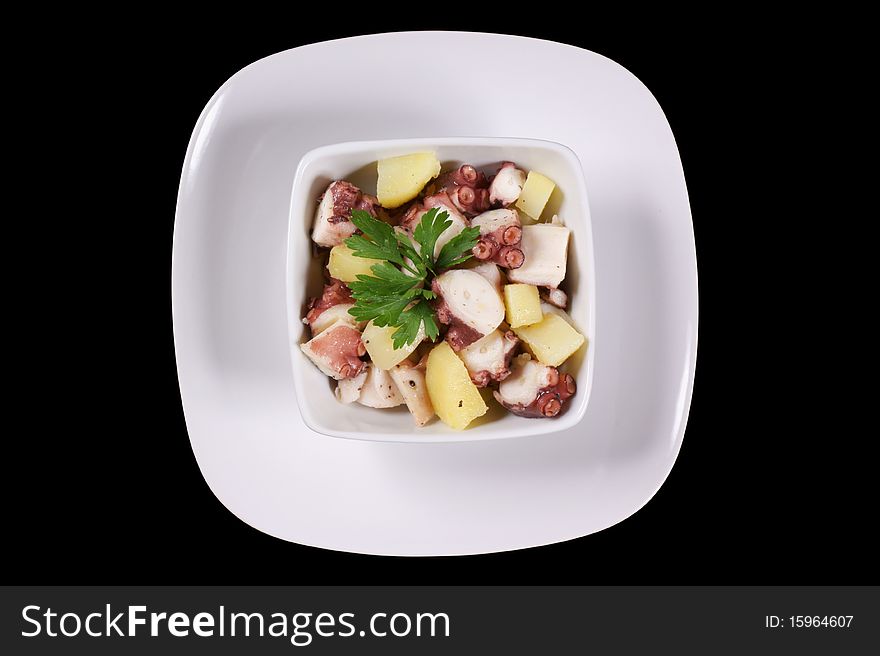 Octopus With Potatoes Served In A White Dish