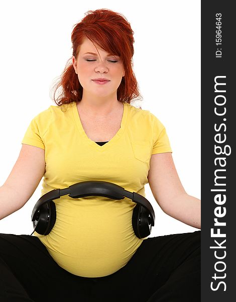 Beautiful pregnant 23 year old american woman with headphones on belly over white. Beautiful pregnant 23 year old american woman with headphones on belly over white.