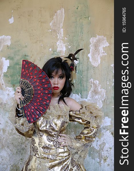Chinese woman wearing victorian costume holding a fan, shoot at grunge background. Chinese woman wearing victorian costume holding a fan, shoot at grunge background