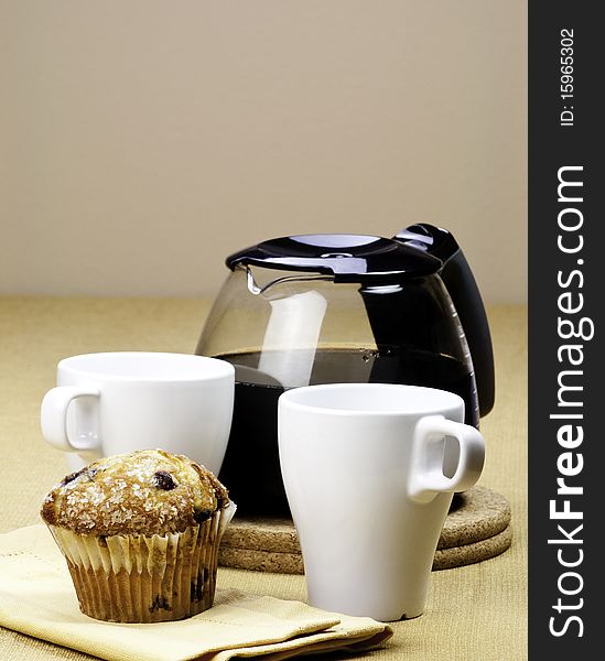 A pot of coffee and a fresh muffin. A pot of coffee and a fresh muffin
