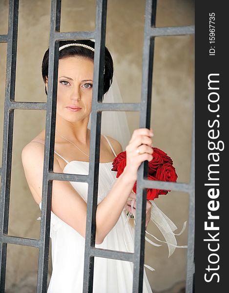 Bride with roses stand for an old wall