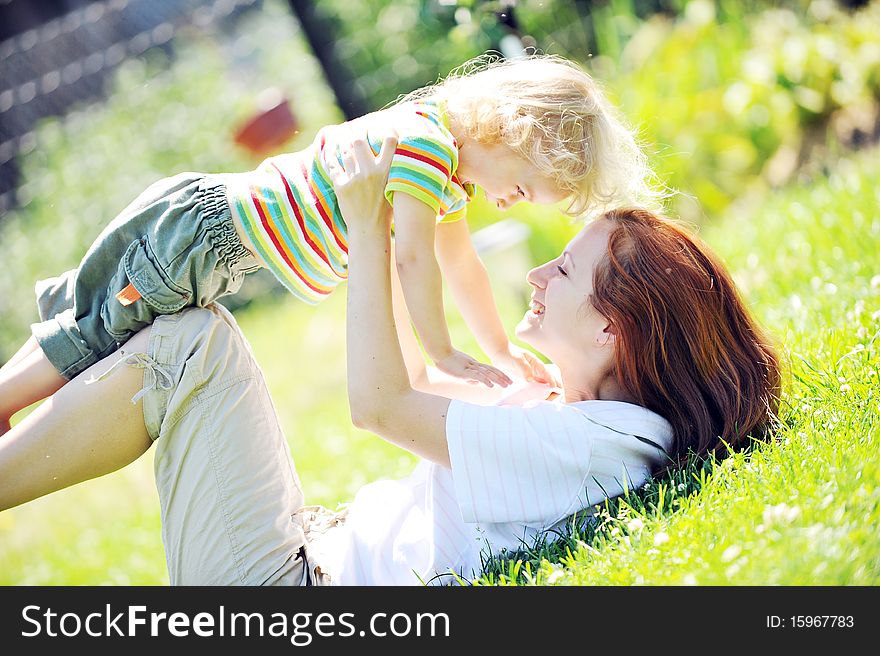 Beautiful young mother with her daughter playing on grass . summer. Beautiful young mother with her daughter playing on grass . summer.