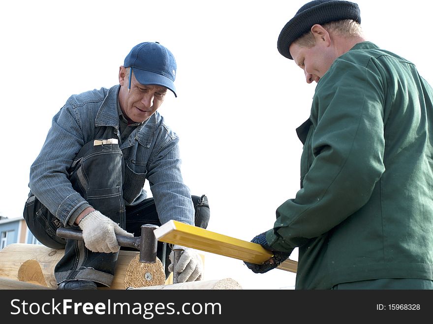 Carpenters works on the wall of log cabin. Carpenters works on the wall of log cabin