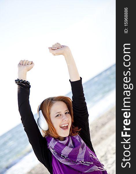 Portrait of red-haired girl in cap with headphone on the beach. Portrait of red-haired girl in cap with headphone on the beach.