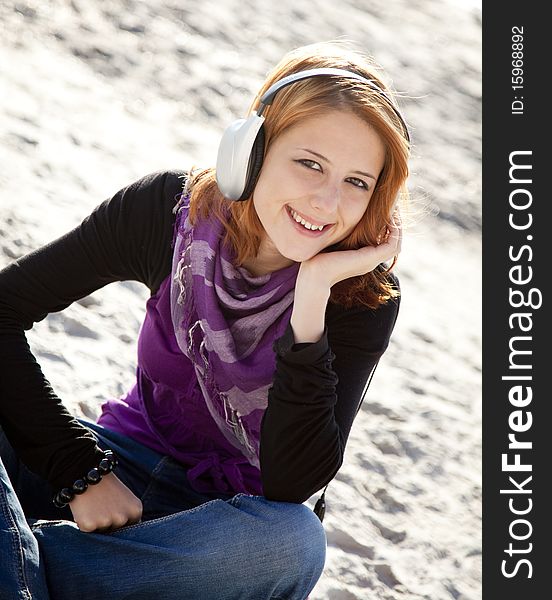 Portrait of red-haired girl in cap with headphone on the beach. Portrait of red-haired girl in cap with headphone on the beach.