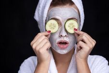 Beautiful Young European Woman Apply Clay Mask On Her Face With Towel On Her Head And Cucumbers On Her Eyes. Beauty Spa Concept Royalty Free Stock Images