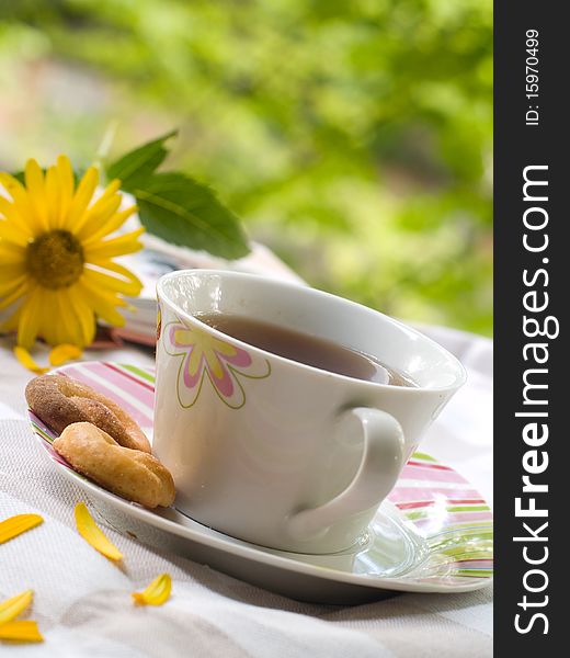 Tea with cookies, the book and flowers on background